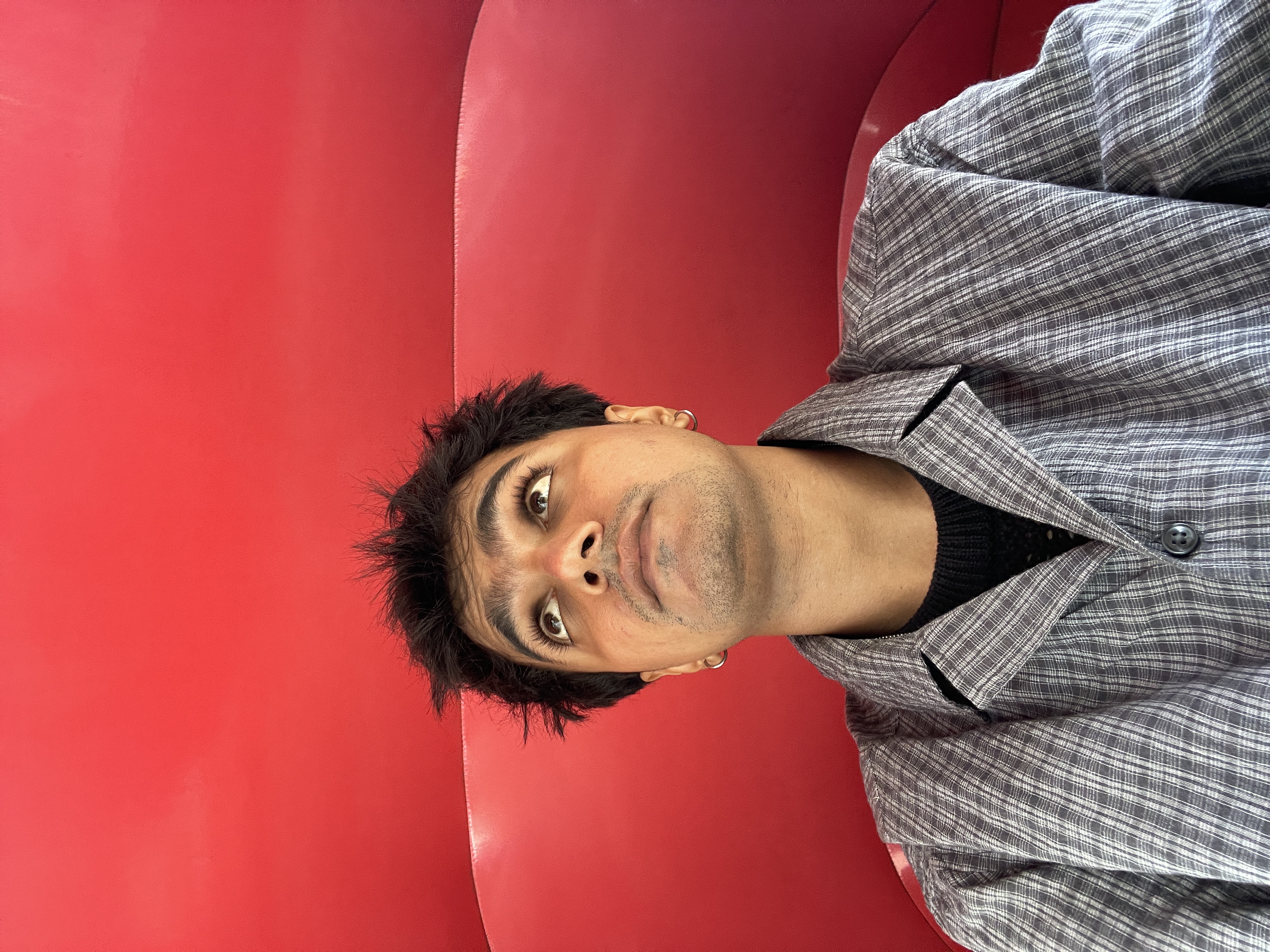 Utkarsh Pachpute, the creative behind Bit8bit, looking upward against a red backdrop